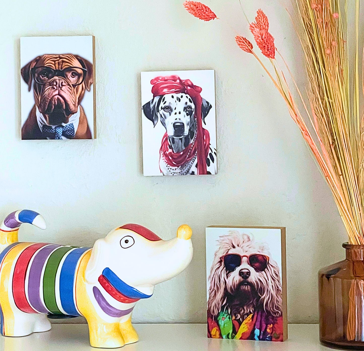 Drei Holzbilder aus der Kollektion Crazy Dogs hängen an einer Wand bzw. stehen auf einem Regal