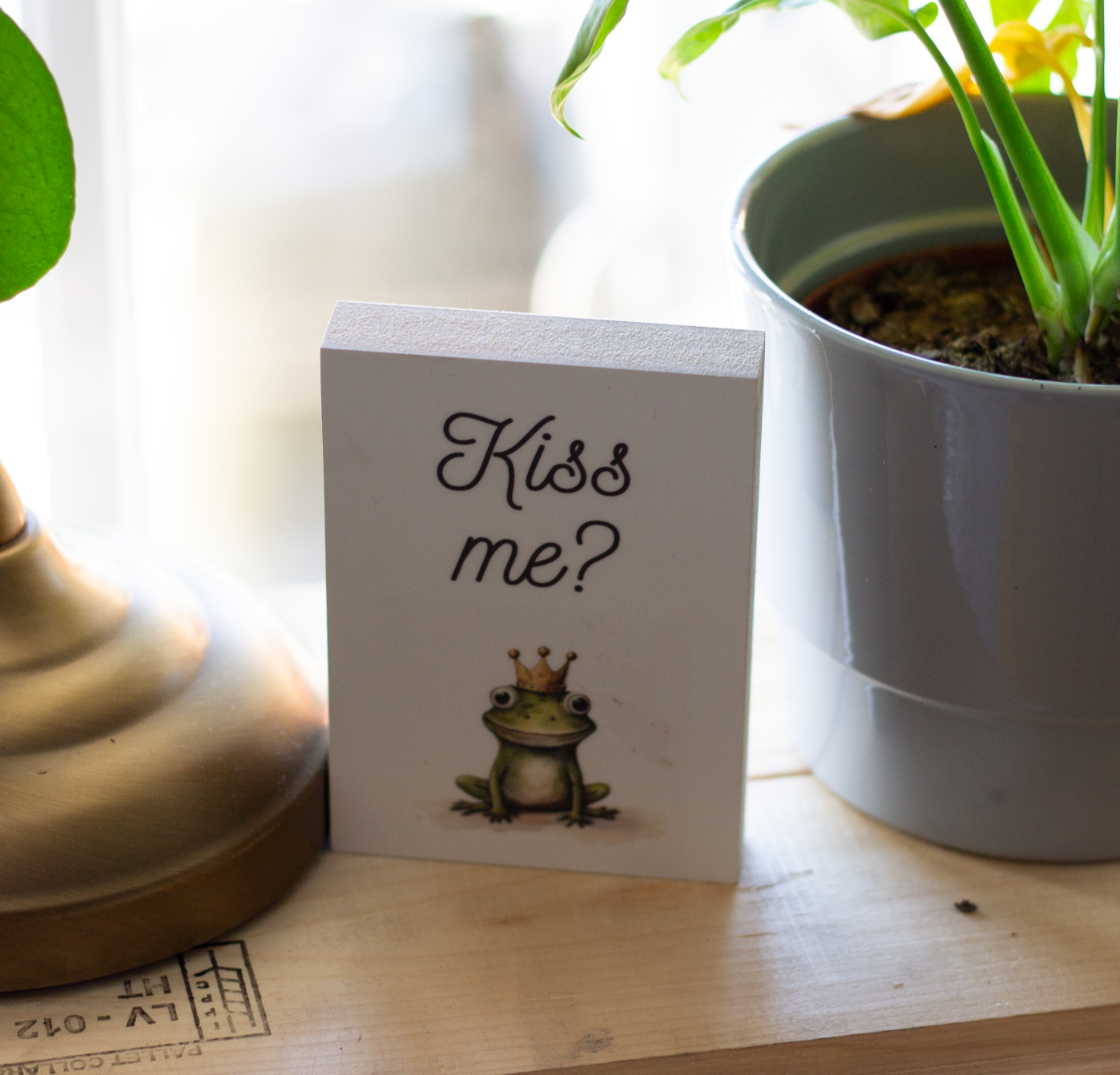 Hlzbild Mit dem Motiv "Kiss me?" neben einer Pflanze stehend