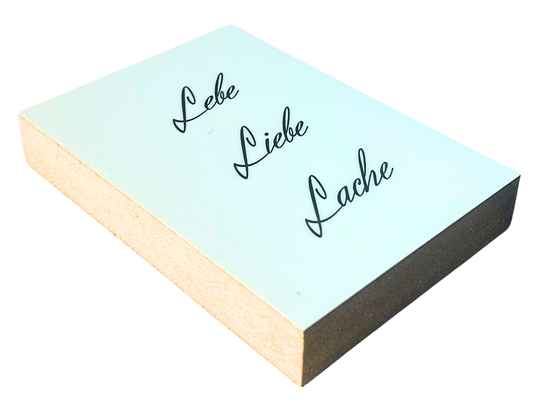 Liegende Ansicht Holzbild mit schwarzer Schrift auf weißem Hintergrund "Lebe. Liebe Lache."
