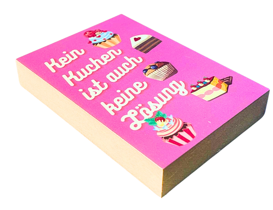 Liegende Ansicht Holzbild mit pinkfarbenem Hintergrund auf dem Zeichnungen mehrerer Kuchenstücke zu sehen sind sowie der Spruch "Kein Kuchen ist auch keine Lösung".