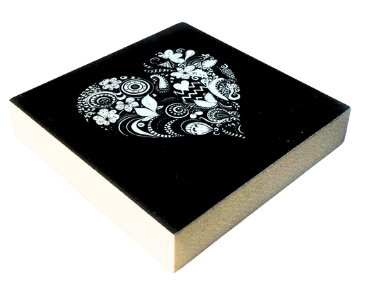 Liegende Ansicht Holzbild mit Herz aus floralen Mustern in Schwarz und Weiß auf schwarzem Hintergund