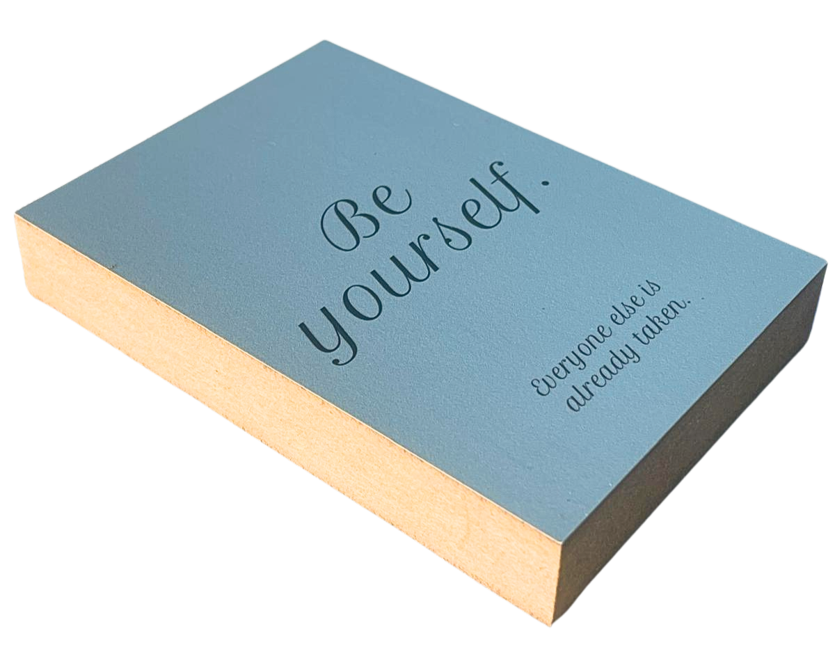 Liegende Ansicht Holzbild mit schwarzer Schrift auf blaugrauem Hintergrund "Be yourself. Everyone else is already taken."