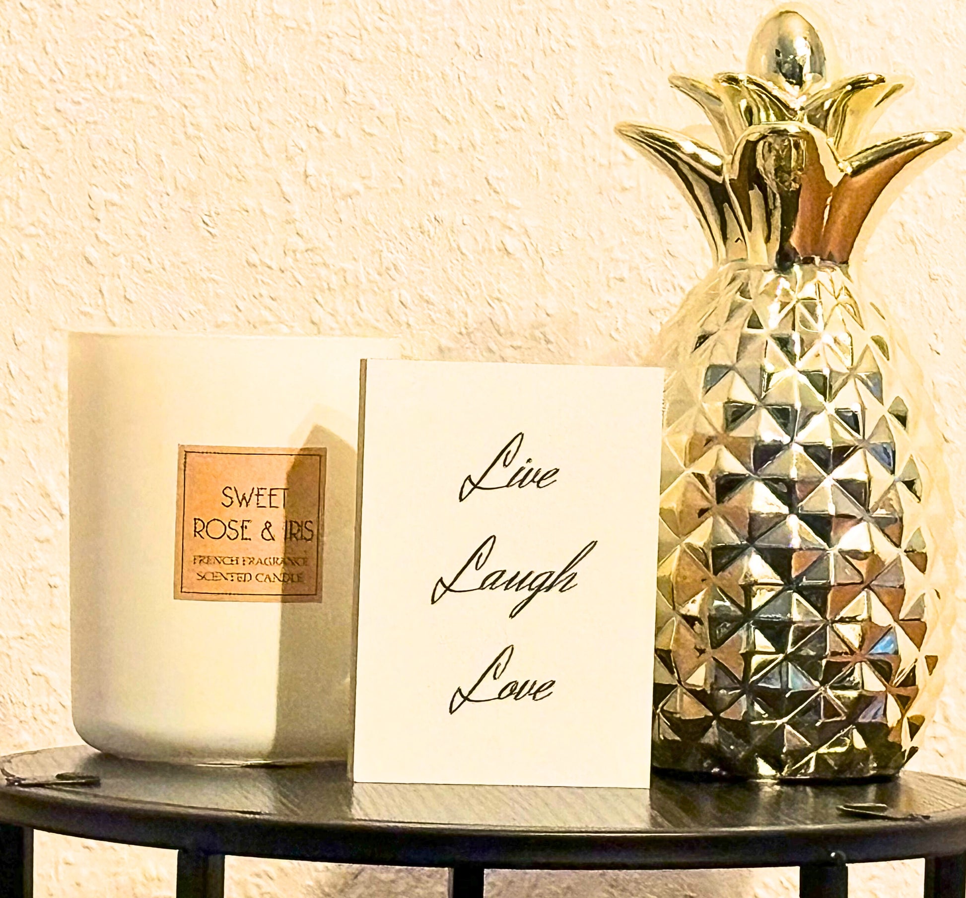 Hlzbild Live Laugh Love" auf einem kleinen isch neben einer Kerze einer goldenen Ananas