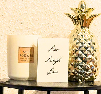 Hlzbild Live Laugh Love" auf einem kleinen isch neben einer Kerze einer goldenen Ananas