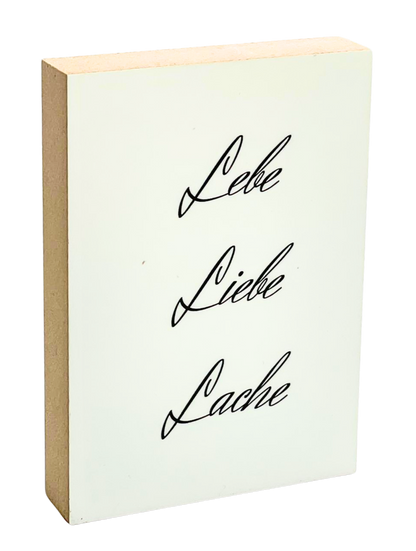 Holzbild 8,5 x 12 cm mit schwarzer Schrift auf weißem Hintergrund "Lebe. Liebe Lache."