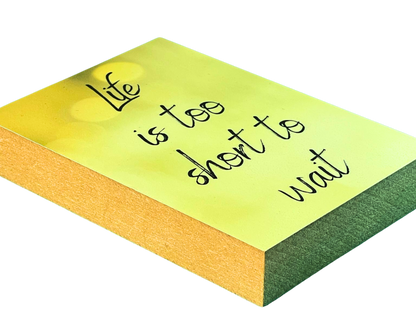 Liegende Ansicht Holzbild mit dem Text "Life is too short to wait" auf gelb gemustertem Hintergrund.